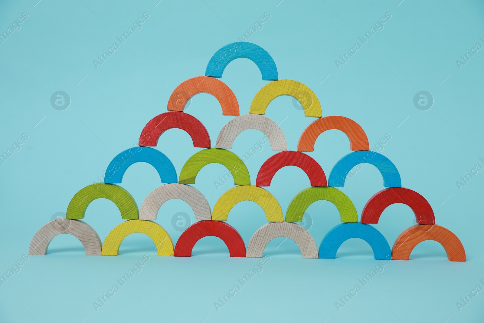 Photo of Colorful wooden pieces of playing set on light blue background. Educational toy for motor skills development