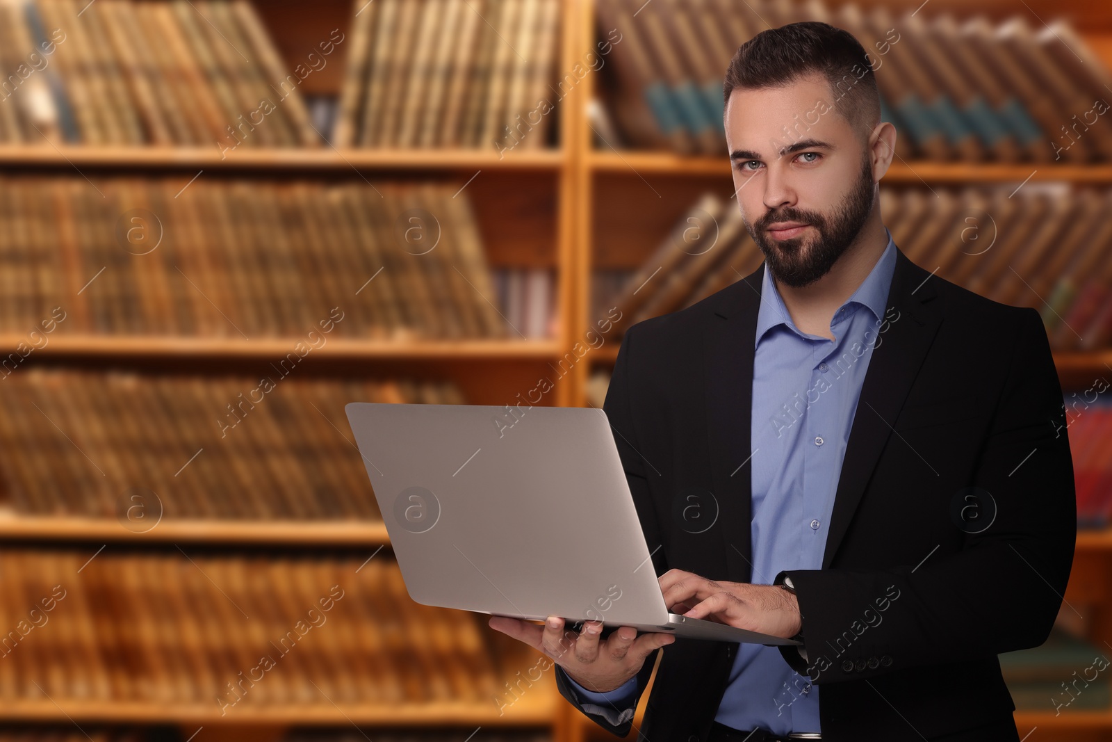 Image of Lawyer with laptop against shelves with books, space for text