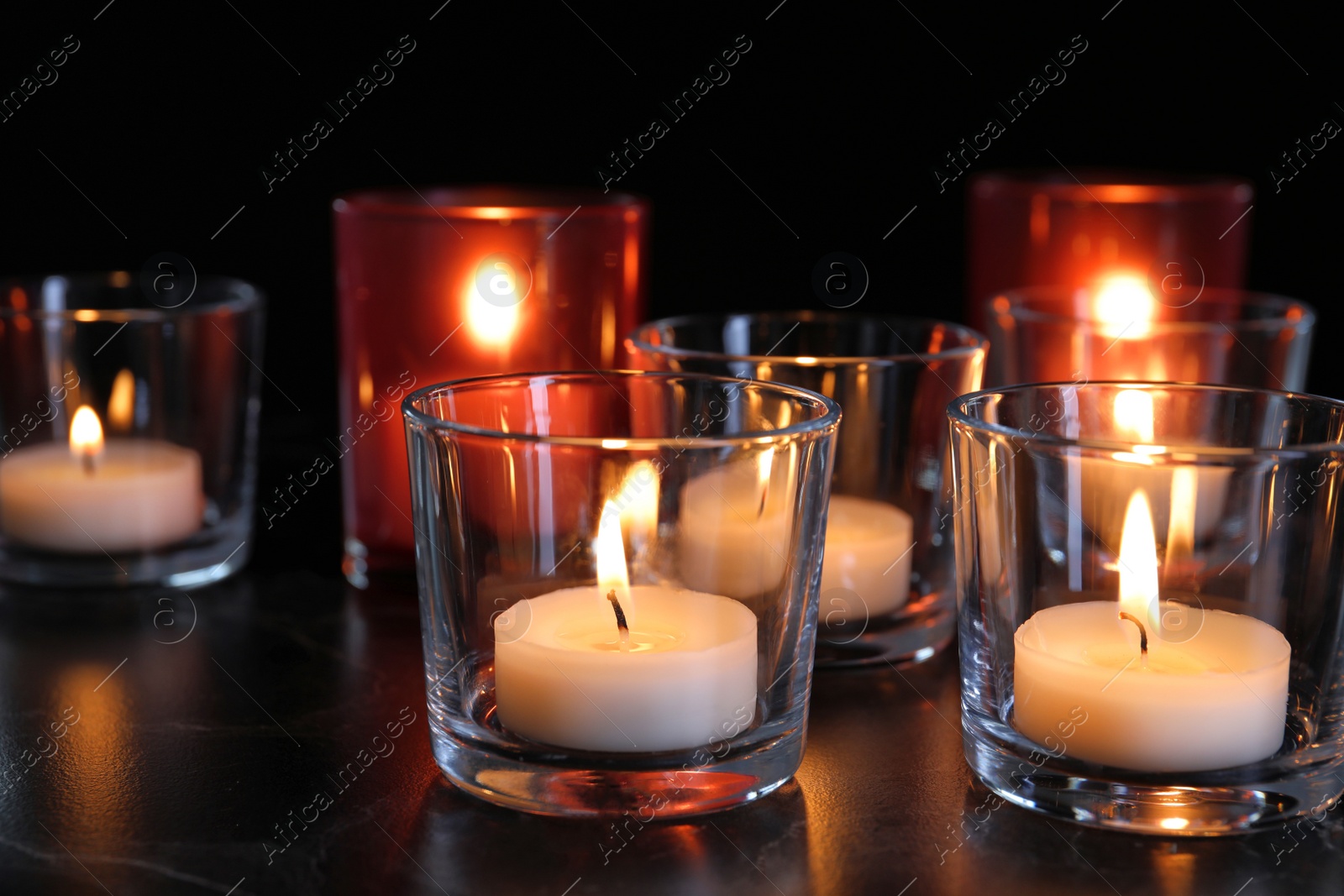 Photo of Burning candles on table in darkness. Funeral symbol