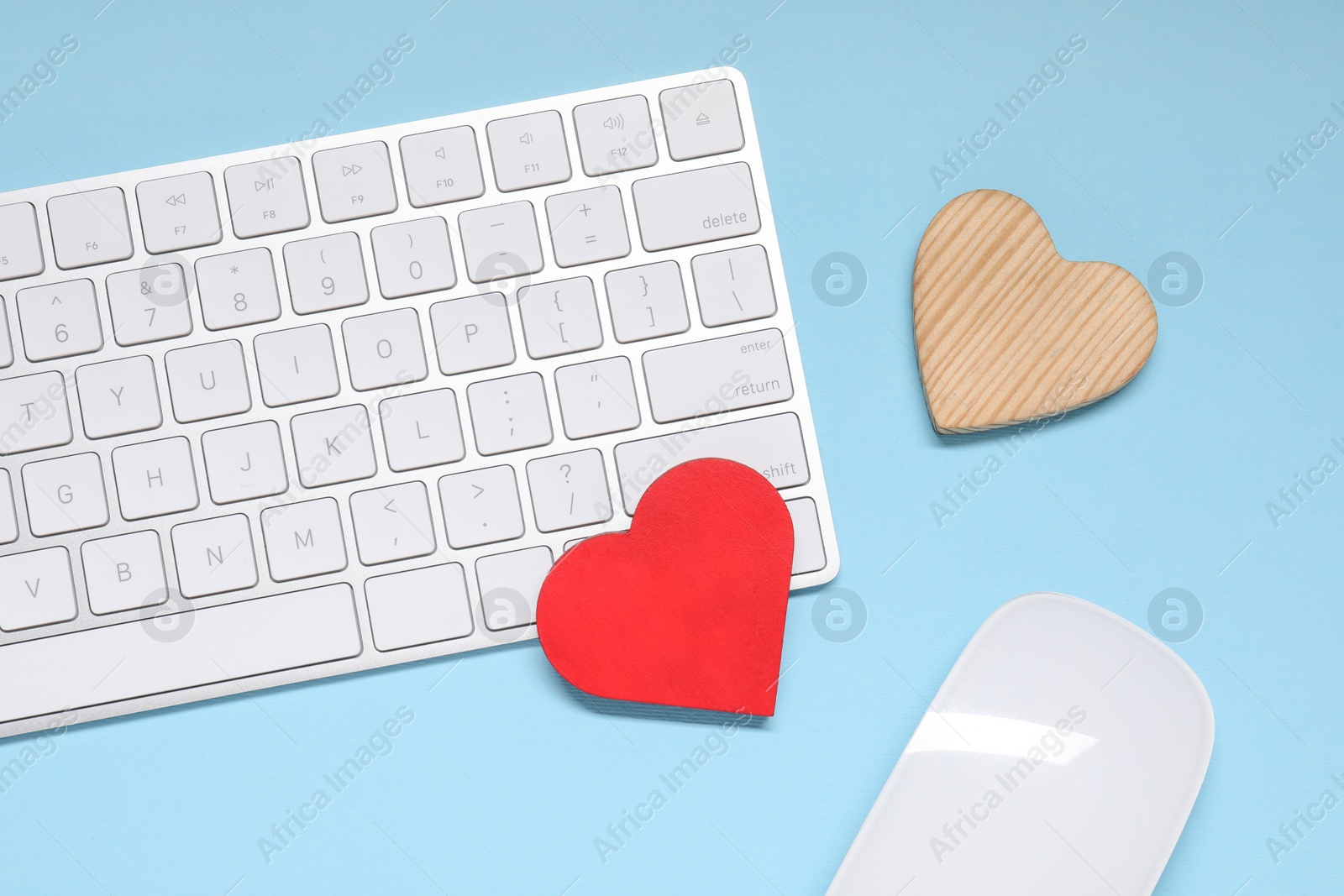 Photo of Long-distance relationship concept. Keyboard, computer mouse and decorative hearts on light blue background, flat lay