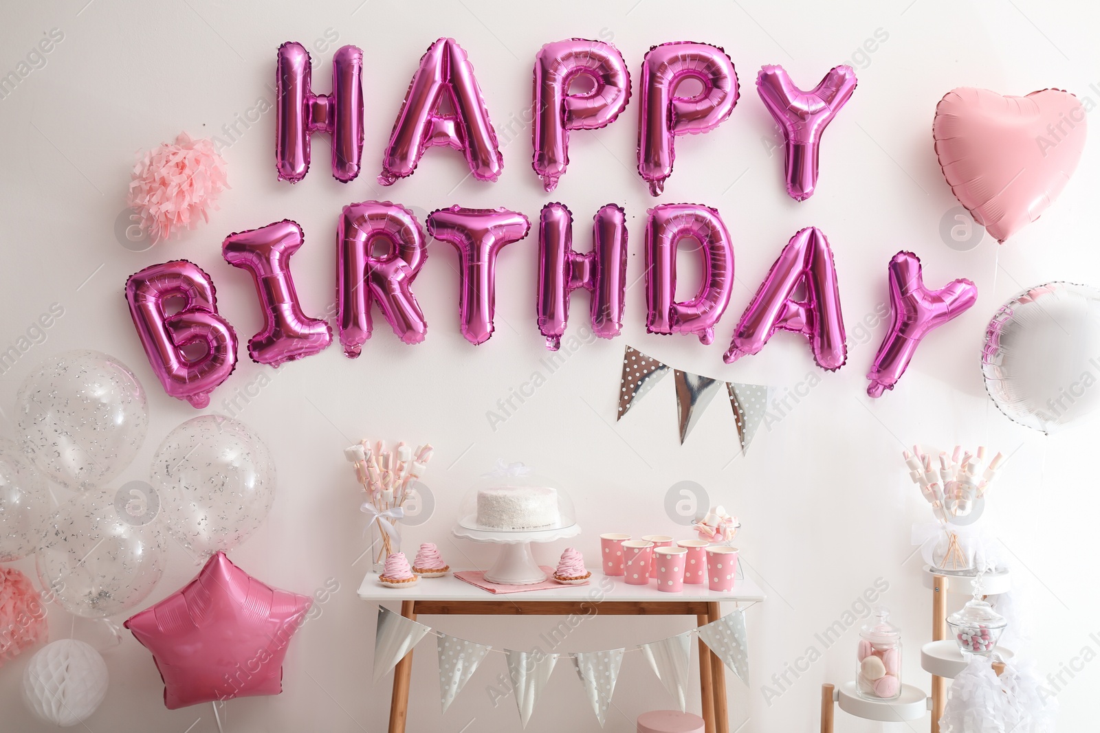 Photo of Phrase HAPPY BIRTHDAY made of pink balloon letters on white wall