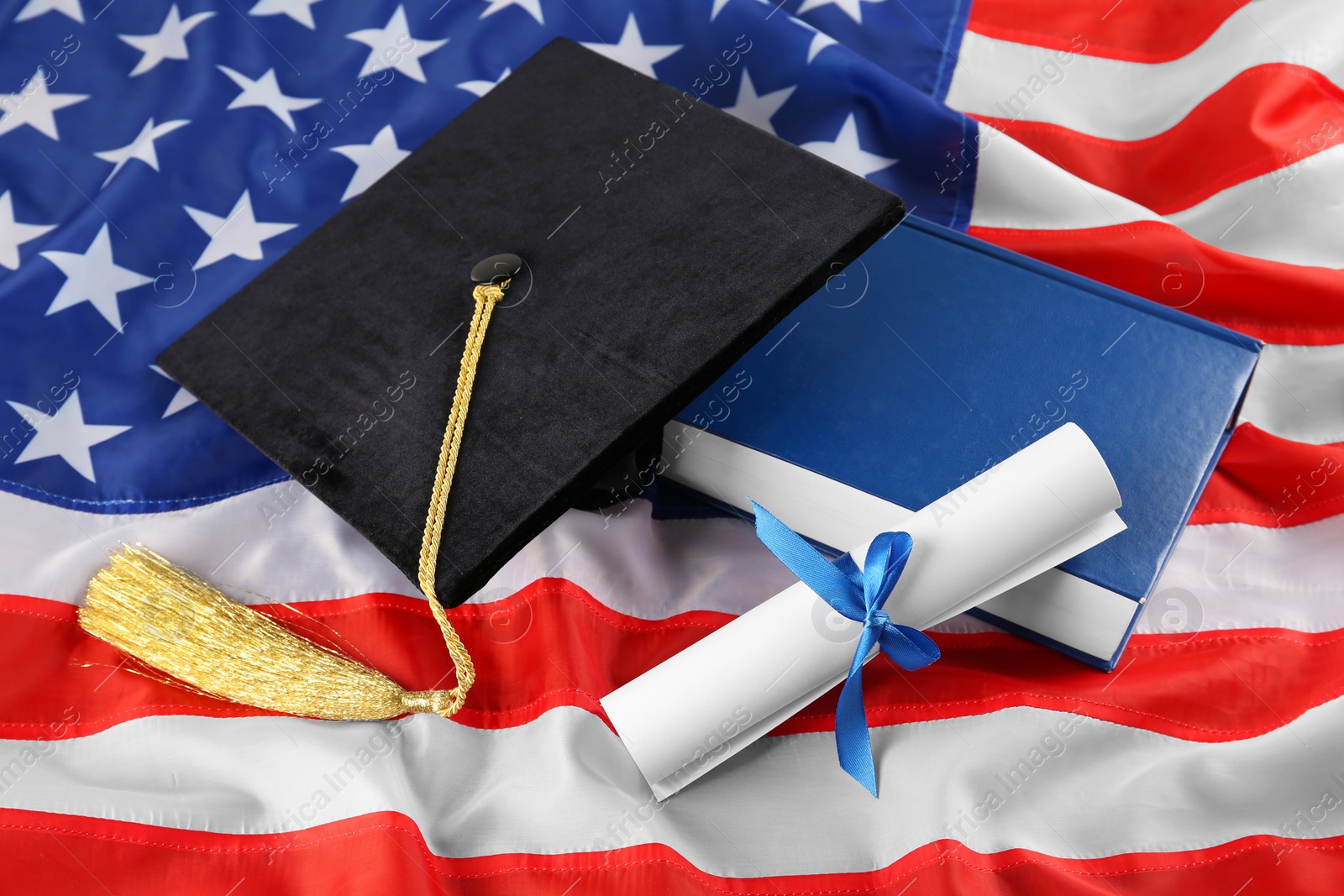 Photo of Black graduation hat, diploma and book on American flag
