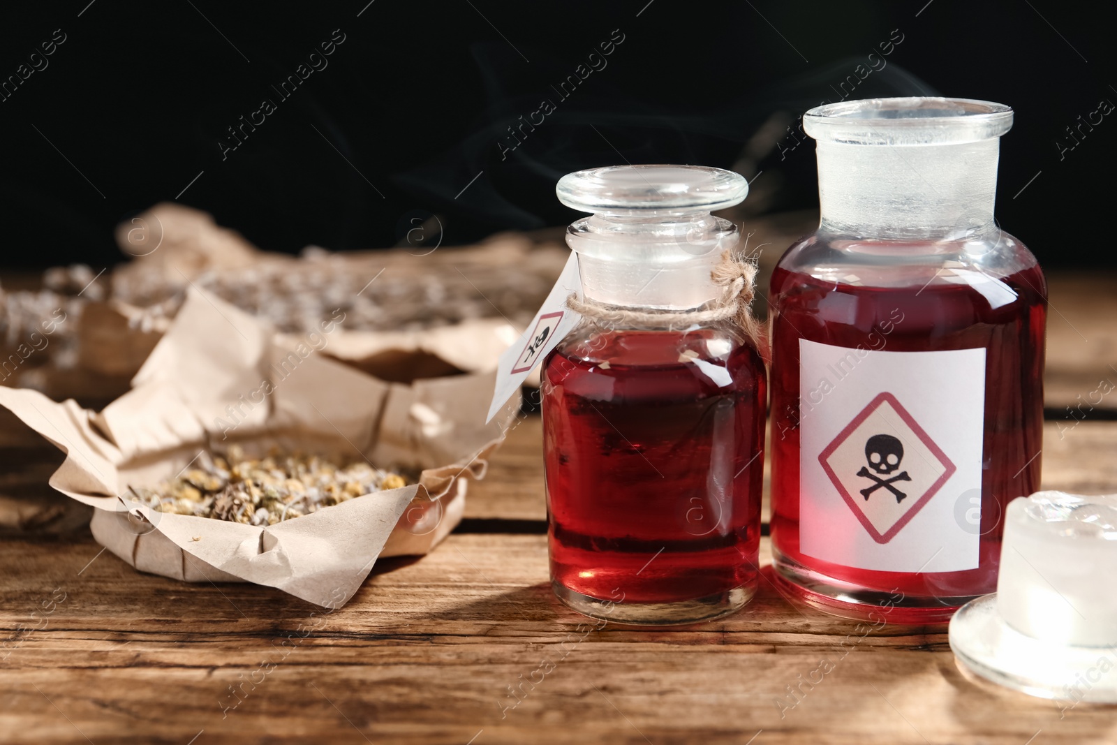 Photo of Glass bottles of poison with warning signs on wooden table