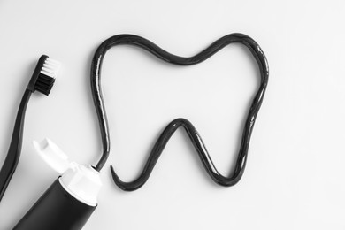 Photo of Tooth drawn with charcoal toothpaste on white background, top view
