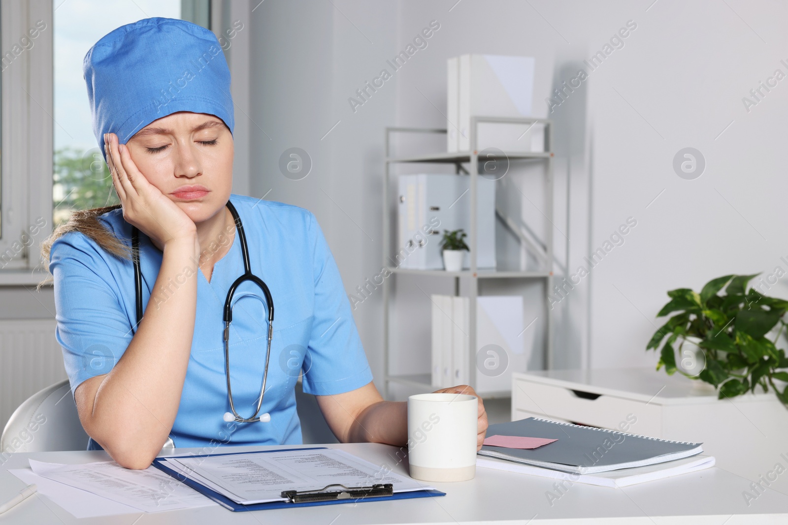 Photo of Tired young doctor sleeping at workplace in office