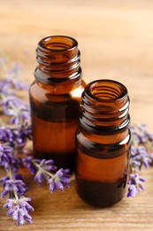 Essential oil and lavender flowers on wooden table, closeup