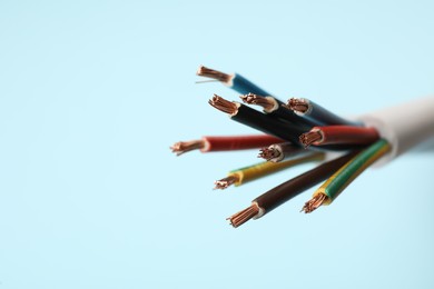 Photo of Many stripped electrical wires on light blue background, closeup