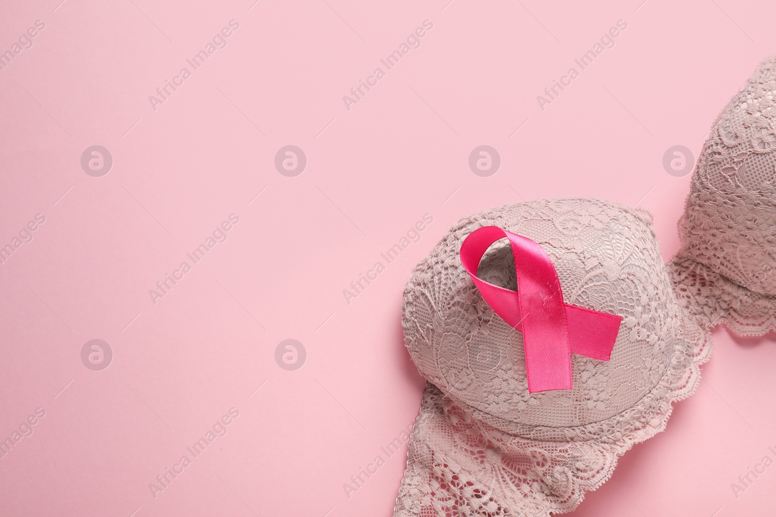 Photo of Pink ribbon and bra on color background, top view with space for text. Breast cancer awareness