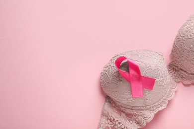 Pink ribbon and bra on color background, top view with space for text. Breast cancer awareness