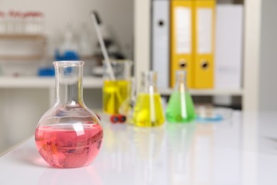 Photo of Laboratory analysis. Flask with pink liquid on white table, space for text