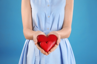 Woman holding decorative hearts on color background, closeup