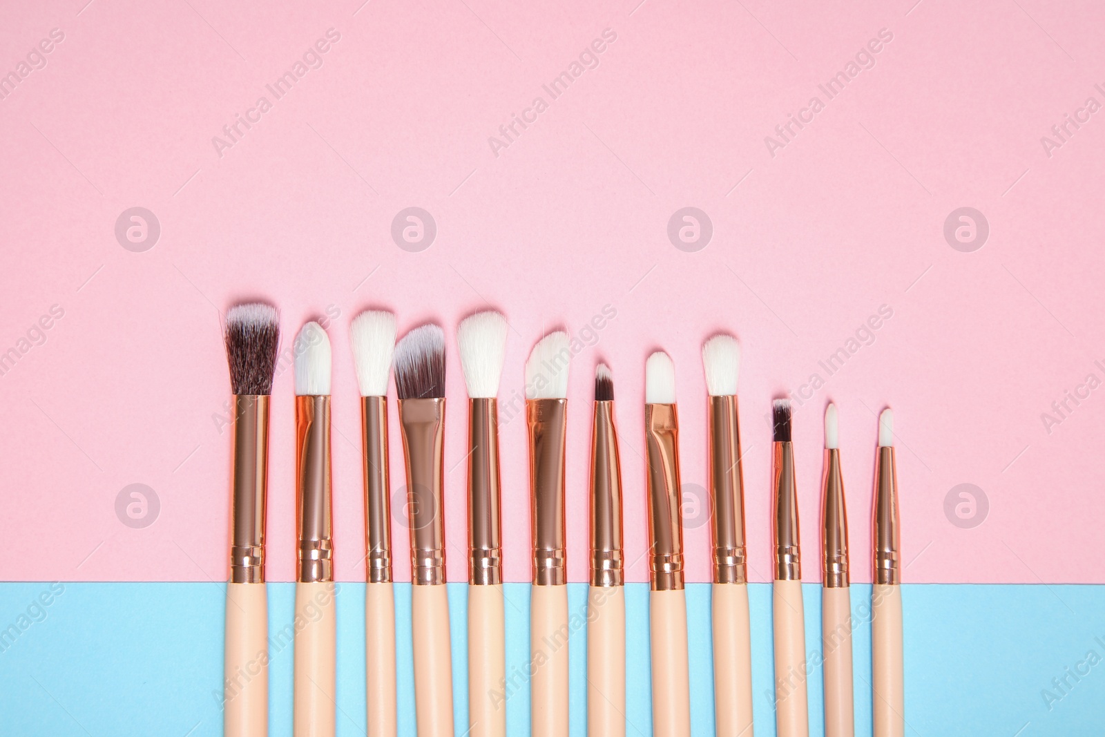 Photo of Flat lay composition with set of makeup brushes on color background. Space for text
