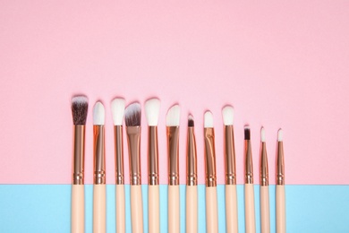 Flat lay composition with set of makeup brushes on color background. Space for text