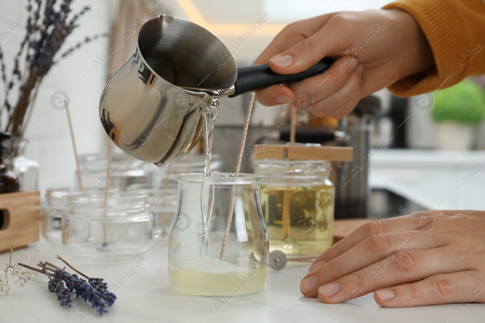 Photo of Woman making candles at white table, closeup