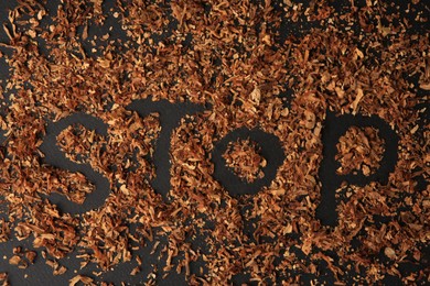 Word Stop made of dry tobacco on dark grey background, flat lay. Quitting smoking concept