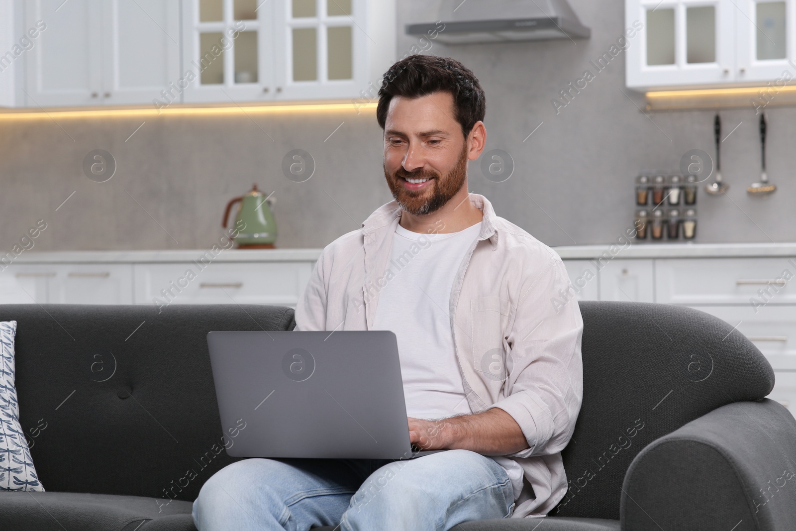 Photo of Man using laptop on couch at home