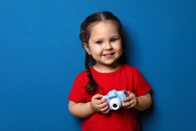 Photo of Little photographer with toy camera on blue background