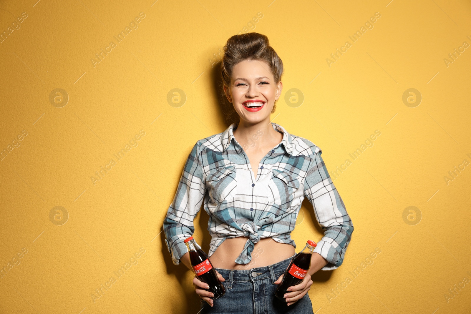 Photo of MYKOLAIV, UKRAINE - NOVEMBER 28, 2018: Young woman with bottles of Coca-Cola on color background