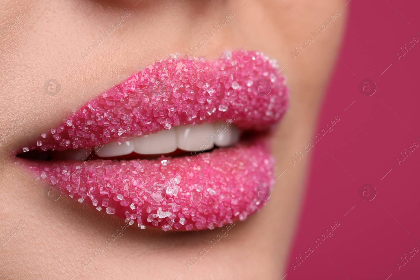 Photo of Young woman with beautiful lips covered in sugar, on pink background, closeup