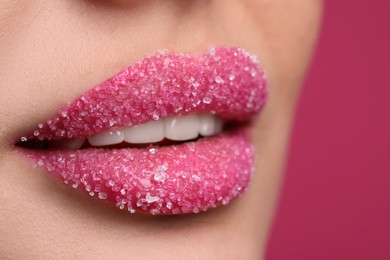 Young woman with beautiful lips covered in sugar, on pink background, closeup