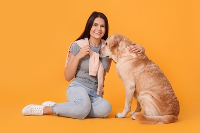Photo of Portrait of happy woman with cute Labrador Retriever on orange background