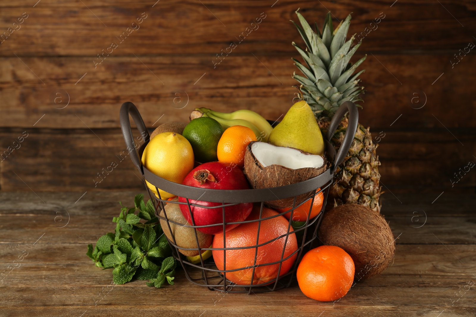 Photo of Metal basket and different ripe fruits on wooden table