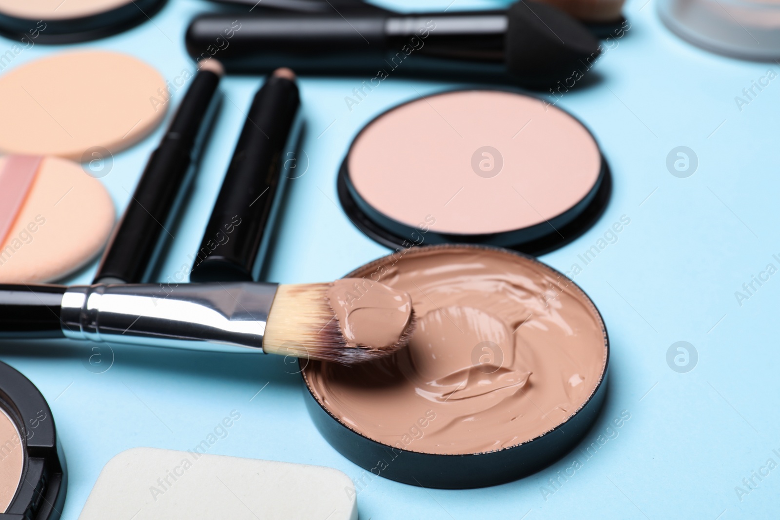 Photo of Composition with skin foundation, powder and beauty accessories on color background