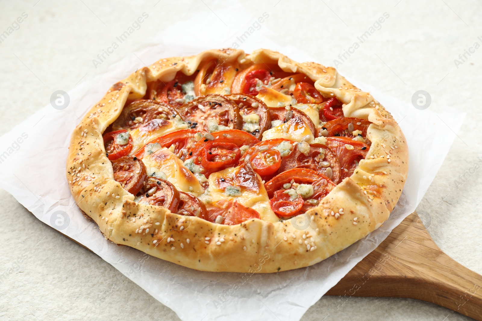 Photo of Tasty galette with tomato and cheese (Caprese galette) on light textured table, closeup