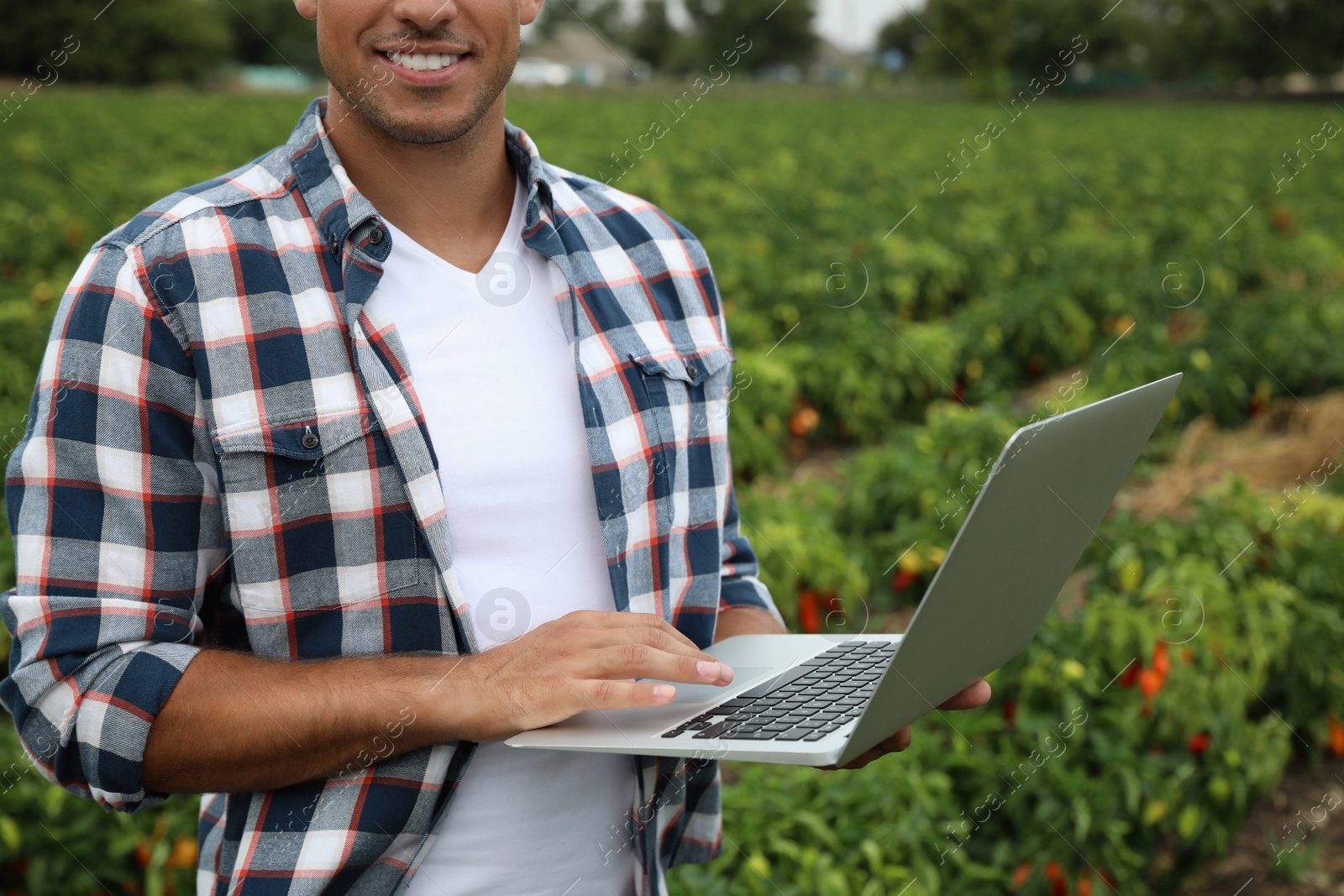 Photo of Man with laptop in field, closeup. Agriculture technology