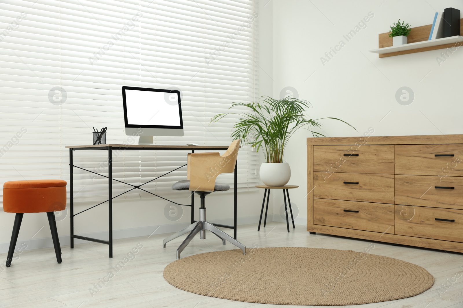 Photo of Stylish office interior with comfortable chair, desk, computer and houseplant