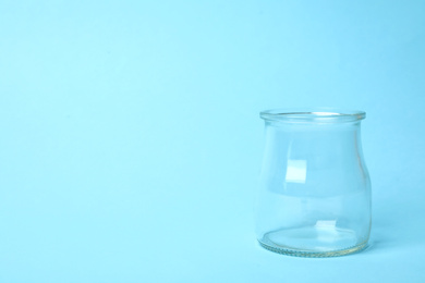 Photo of Open empty glass jar on light blue background, space for text