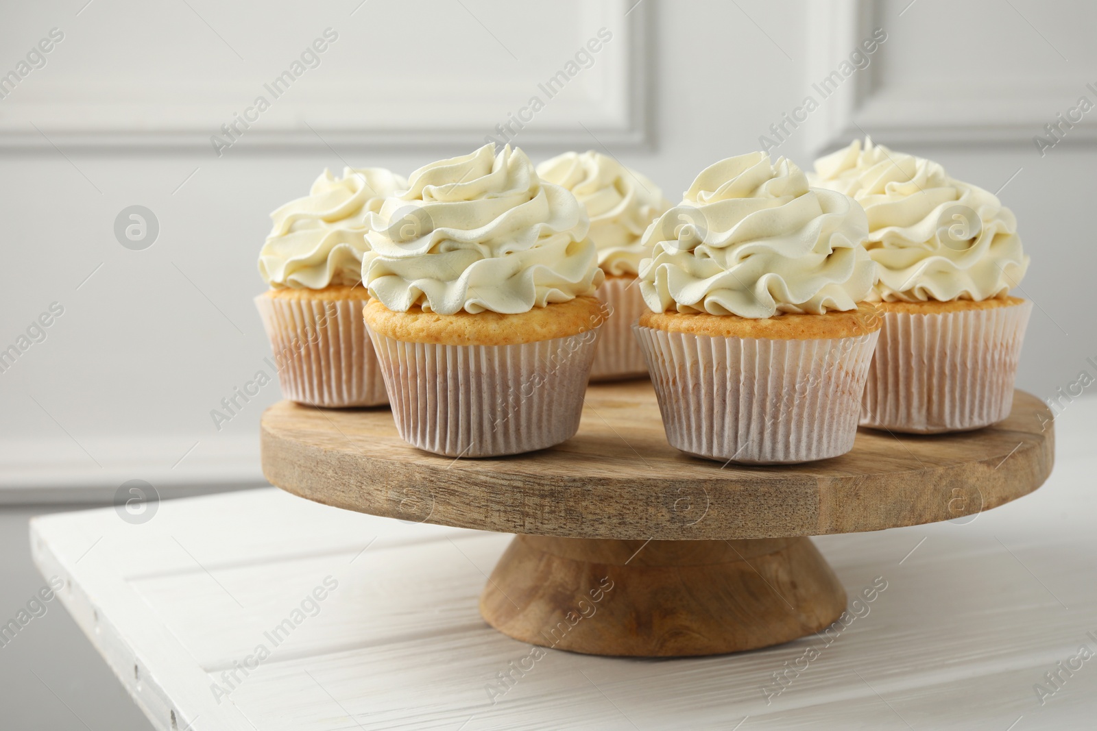 Photo of Tasty vanilla cupcakes with cream on white wooden table