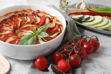 Delicious ratatouille and ingredients on white marble table, closeup