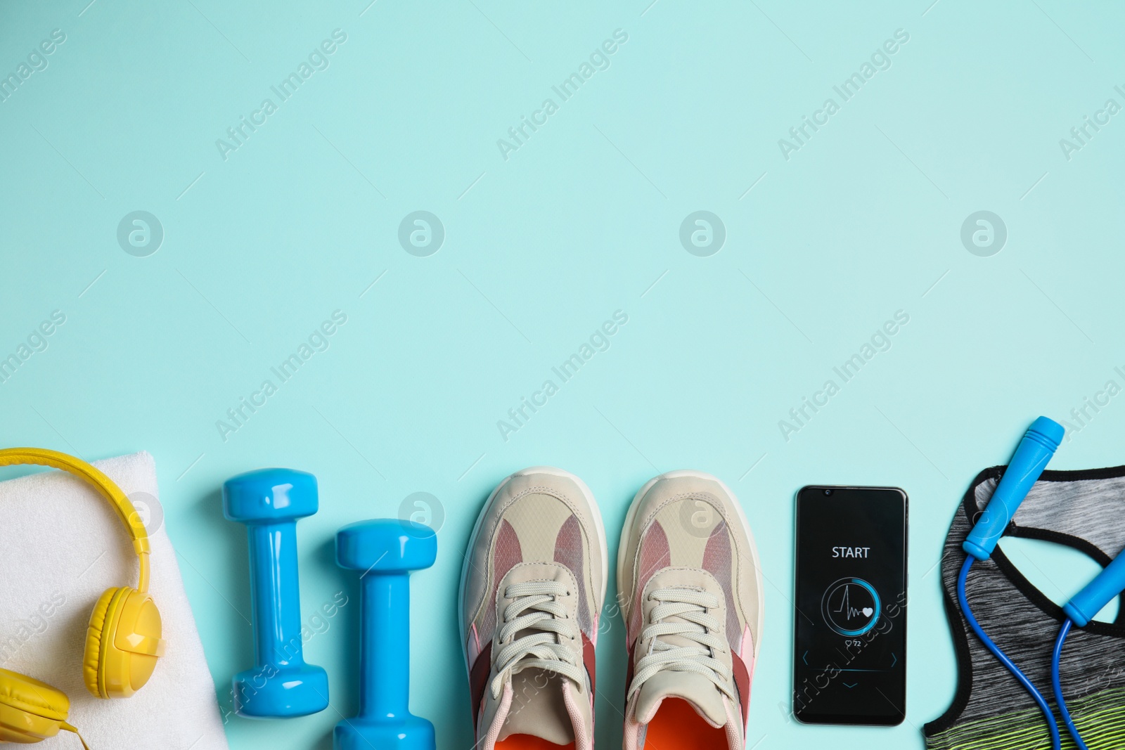 Photo of Flat lay composition with fitness equipment and smartphone on light blue background, space for text