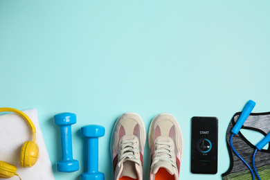 Photo of Flat lay composition with fitness equipment and smartphone on light blue background, space for text