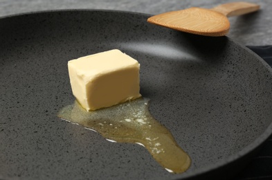 Photo of Frying pan with piece of melting butter and spatula, closeup