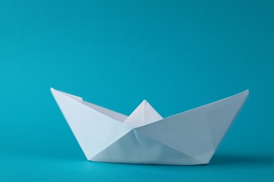 Handmade white paper boat on light blue background. Origami art