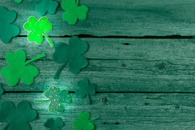 Image of St. Patrick's day. Decorative clover leaves on green wooden background, top view. Space for text