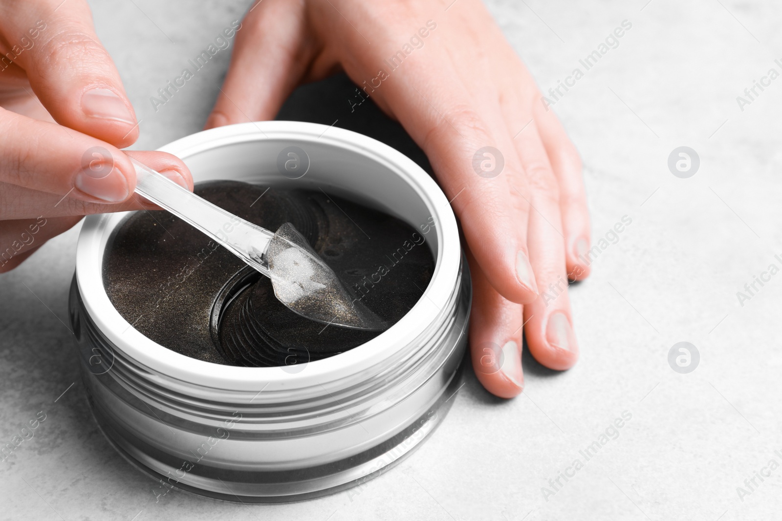 Photo of Woman using under eye patches at light table, closeup. Cosmetic product