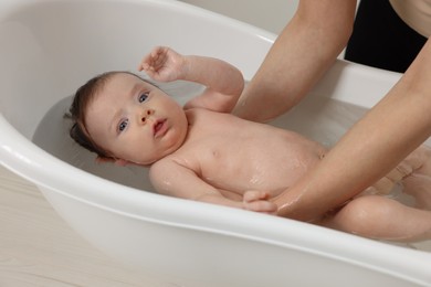 Mother bathing her little baby in bathtub, closeup