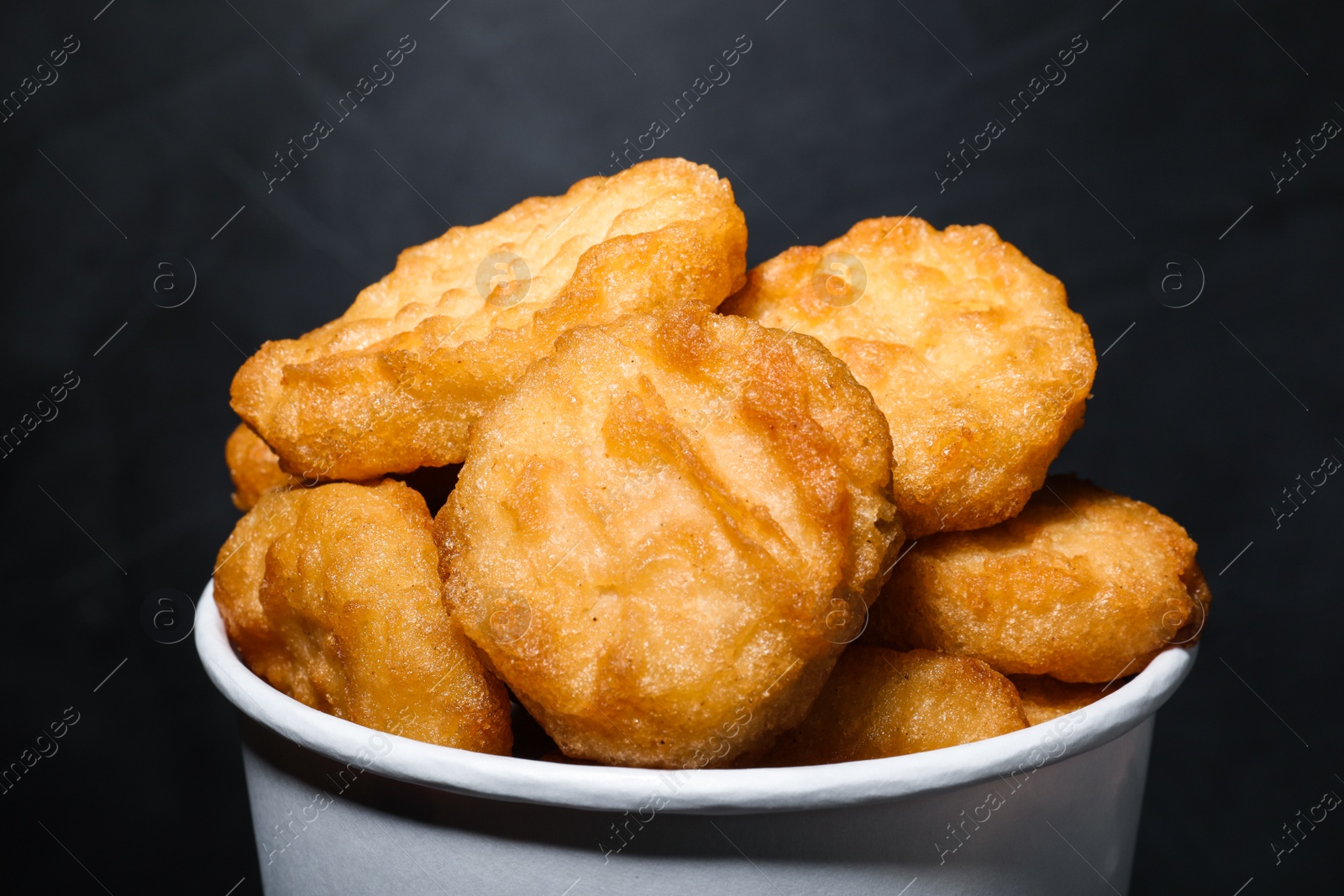 Photo of Bucket with delicious chicken nuggets on grey background, closeup