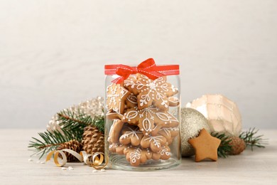 Tasty Christmas cookies in glass jar and festive decor on beige wooden table