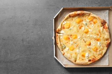 Photo of Cheese pizza in carton box on grey background, top view with space for text. Food delivery service
