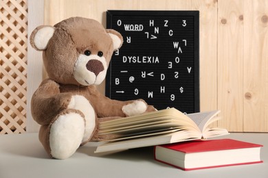 Photo of Teddy bear, black letter board with word Dyslexia and books on light table