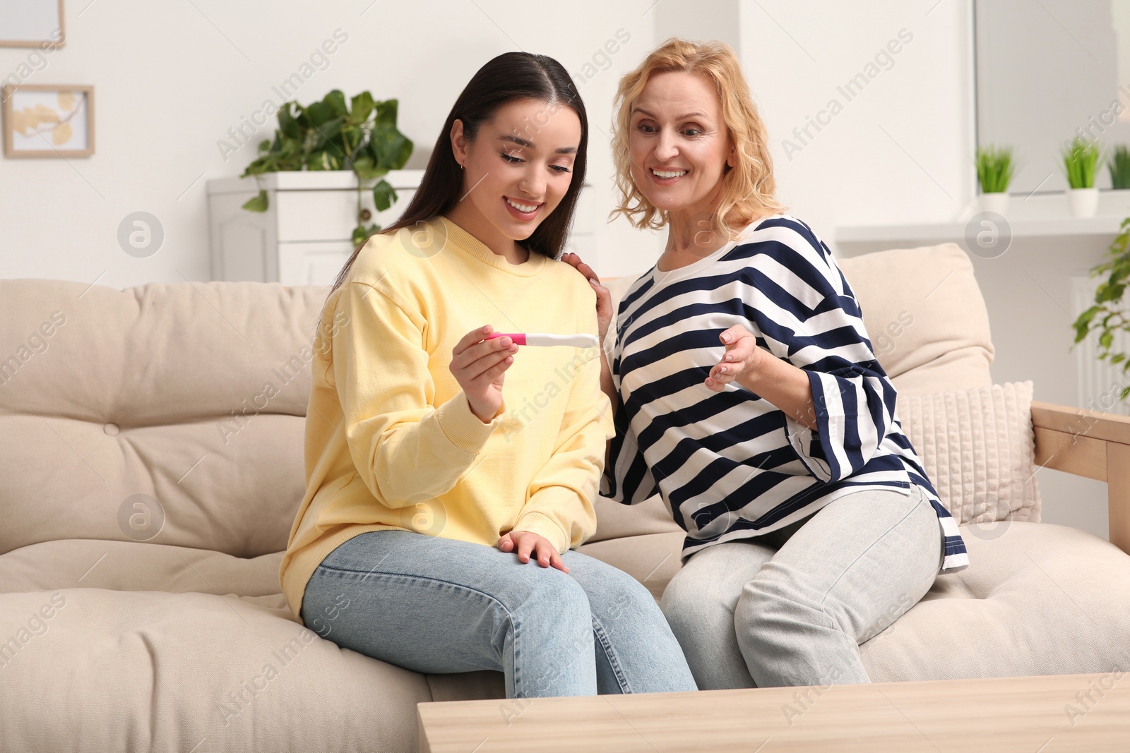 Photo of Happy pregnant woman spending time with her mother at home. Grandparents' reaction to future grandson