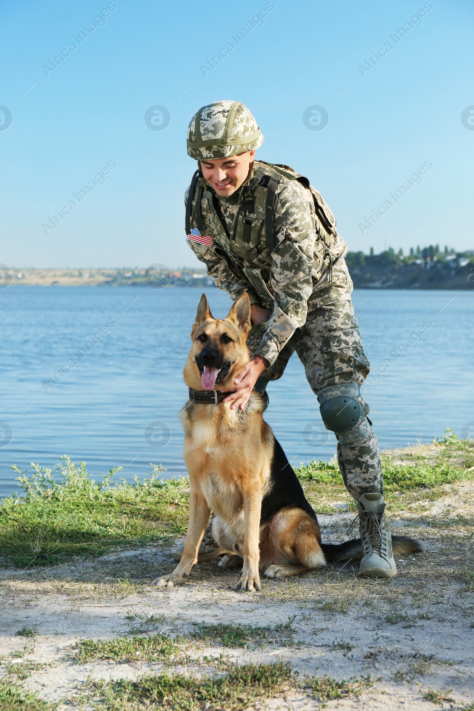 Photo of Man in military uniform with German shepherd dog near river