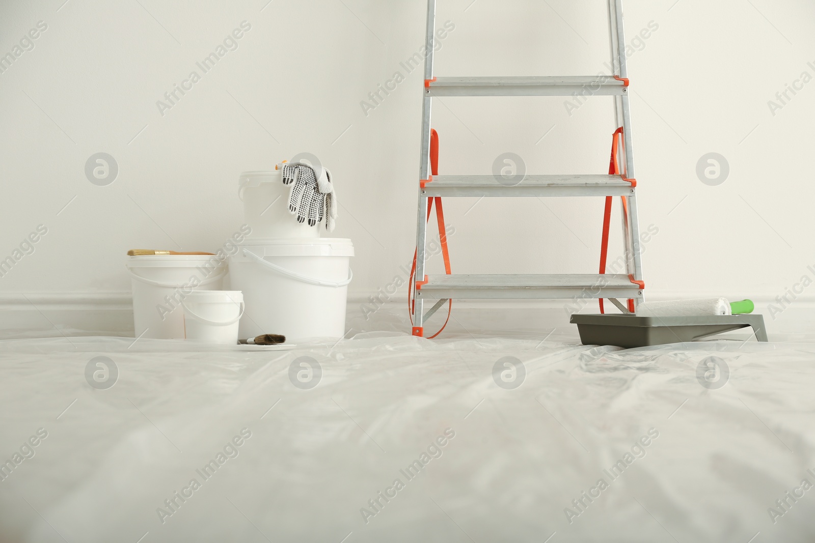 Photo of Stepladder and different tools near wall in room. Interior renovation