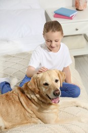 Photo of Cute child with her Labrador Retriever on bed at home. Adorable pet