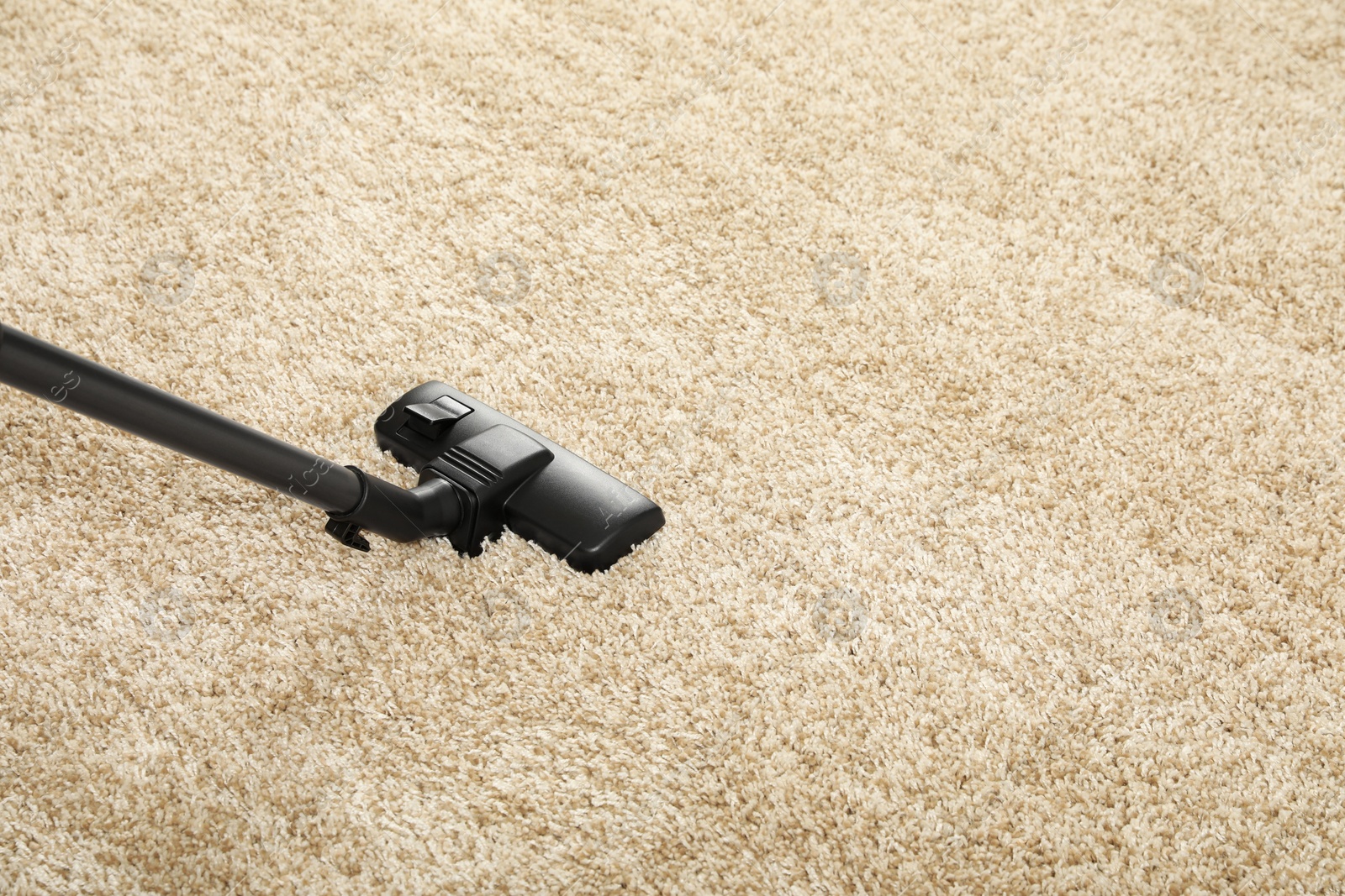 Photo of Removing dirt from beige carpet with modern vacuum cleaner. Space for text