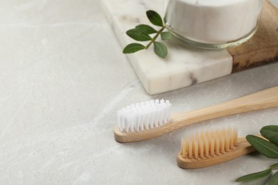 Photo of Bamboo toothbrushes and jar of baking soda on light grey marble table, space for text